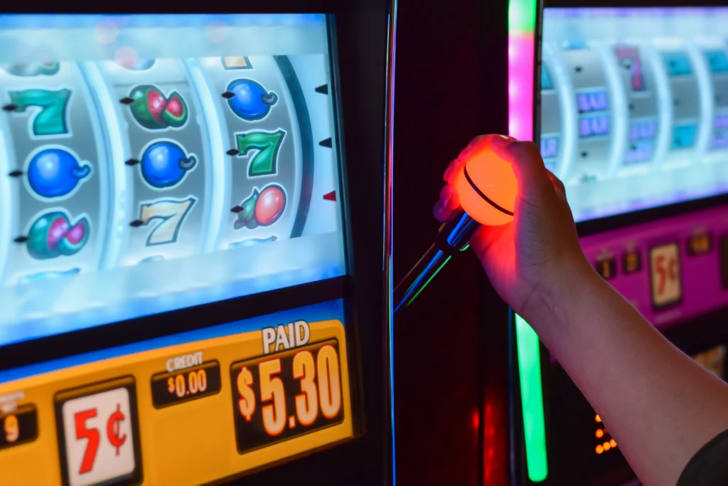 Slot gombját megnyomó kéz, slot tippek és bankroll stratégia illusztrációja